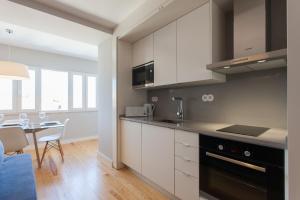 里斯本FLH Principe Real Luxus Apartments的一间厨房,内设白色橱柜和一张桌子