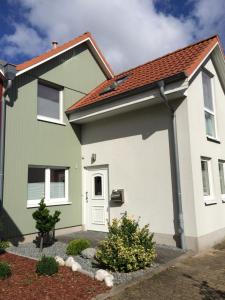 格赖夫斯瓦尔德Ferienhaus am Yachthafen的绿色白色的房屋,有红色的屋顶