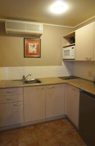 奥克兰康沃尔公园汽车旅馆的厨房配有白色橱柜、水槽和微波炉