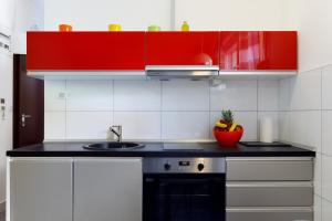 斯普利特方舟海滩公寓的一间带红色橱柜和水槽的厨房