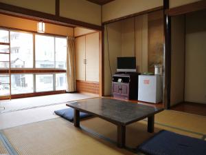 广岛Kimatsu Ryokan的客厅配有桌子和冰箱