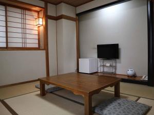 广岛Kimatsu Ryokan的客厅配有木桌和电视。