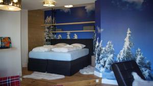 因泽尔ALPENLIEBE Design Hotel的卧室配有一张床上,墙上挂着雪覆盖的树木