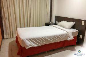 维多利亚Triângulo Apart Hotel的一张位于酒店客房内的床铺,配有白色毯子和枕头