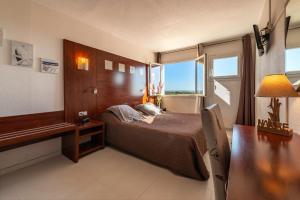 马瑟伊兰沙丘酒店的一间卧室配有一张床、一张书桌和一个窗户。