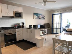 卡门港Apartment Layla的厨房配有白色橱柜、桌子和用餐室。
