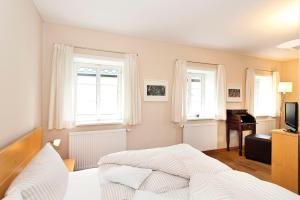 巴特尚道Fährmannhaus的一间卧室设有床、两扇窗户和一架钢琴