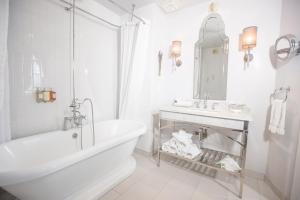 洛杉矶卡尔弗酒店的白色的浴室设有浴缸和水槽。