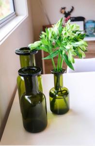 怀蒂昂格WoodyHanger Lodge的三个绿花瓶,桌子上放着鲜花