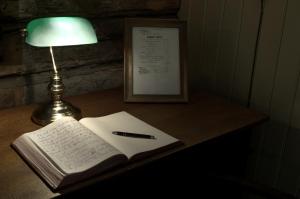 赛尔尤尔Seljord Hotel - Unike Hoteller的一张桌子,上面写着一本书,还有一根笔和一盏灯