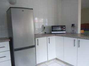 姆巴巴内Liz' Cottage的厨房配有白色橱柜和冰箱。