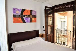 格拉纳达崔斯特乐膳食公寓酒店的卧室配有一张床,墙上挂有绘画作品