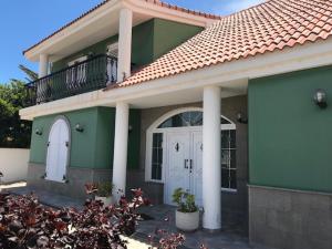 特尔德Chalet Canarias的绿色的房子,设有白色的门和阳台