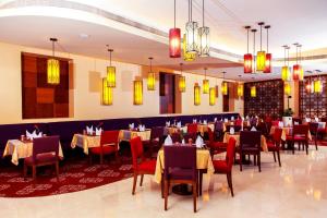多哈大富豪酒店 的用餐室配有桌椅和吊灯。