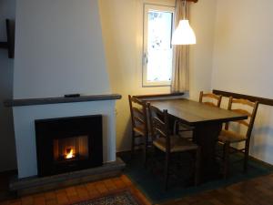 洛迦诺天堂度假公寓的一间带壁炉和桌椅的用餐室