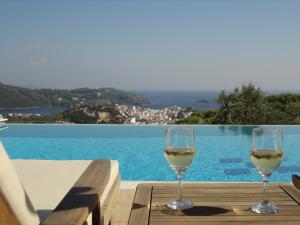斯基亚索斯镇Skiathos Garden Cottages的两杯白葡萄酒坐在桌旁的游泳池边