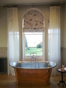 MantonCleatham Hall的窗户客房内的大型木制浴缸
