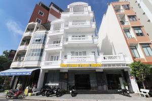 芽庄Nha Trang Pearl Hotel的一座白色的建筑,前面停有摩托车