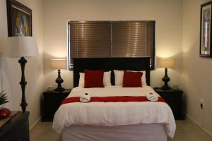 哈特比斯普特Millennium Body Guards Guesthouse的一间卧室配有一张带红色枕头的大床