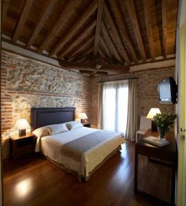 Los Santos de la Humosa罗马教皇酒店的一间卧室设有一张大床和砖墙