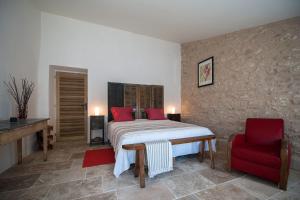 博尼约La Ressence Luberon的一间卧室配有一张床和一张红色椅子