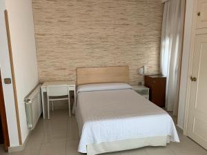 瓦尔德莫罗塞万堤斯旅馆的一间小卧室,配有一张床、一张桌子和椅子
