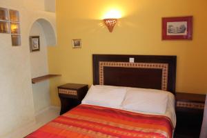 丹吉尔达而奥玛卡延旅馆的小卧室配有带条纹毯子的床