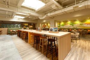 高松WeBase TAKAMATSU的餐厅设有长长的酒吧,配有凳子