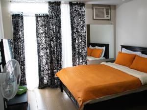 马尼拉4Q tower D Manhanttan Heights Cubao QC的一间卧室配有带橙色枕头和窗帘的床