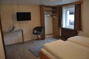 贝旺伯格霍夫公寓的一间卧室配有一张床、一把椅子和电视