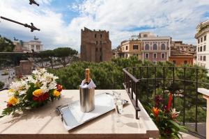 罗马罗马诺酒店的阳台上的桌子上放着一瓶葡萄酒和鲜花