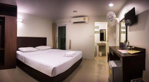 华欣阳光旅馆的卧室配有白色的床和电视。