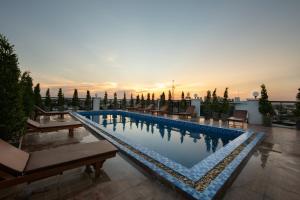 万象Azalea Parkview Hotel的一个带长椅的游泳池,享有日落美景