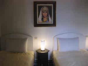 非斯里亚德沙巴酒店的一间卧室设有两张床,墙上挂着一幅画