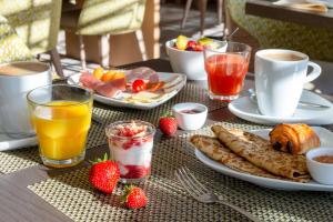 坎佩尔Hôtel Ginkgo - SPA Biloba的餐桌上摆放着早餐食品和饮料