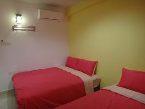马六甲法摩萨2号民宿的小客房内的两张床,配有红色床单
