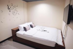 曼谷考山站旅舍的一间卧室配有一张带白色床单的床和一台电视。