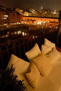佛罗伦萨迪格里奥拉费酒店的一张白色的床,晚上在阳台上配有枕头