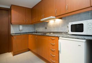 卡尼略Apartamentos Turísticos Roc Del Castell的厨房配有木制橱柜和白色微波炉