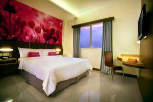 日惹库苏曼尼卡拉大街酒店的一间卧室配有一张大床和一幅红色的画作