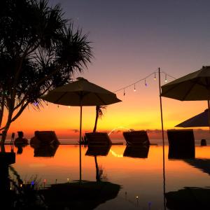 蓝梦岛Twilight Ceningan的日落前带椅子和遮阳伞的游泳池