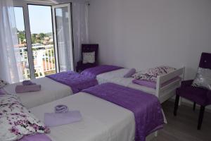 赫瓦尔Villa Zorana hostel的客房设有三张带紫色床单的床和一个阳台