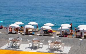 洛卡卢美拉Casa del Melograno 40的海滩上设有桌椅和白色遮阳伞