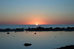 雷阿尔蒙特A due passi dal mare的海上的日落,岩石在水中
