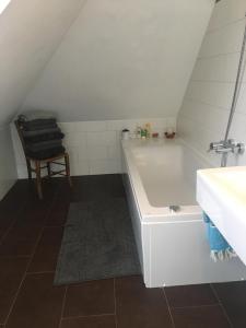 慕尼黑Helle und ruhige Dachgeschosswohnung的带浴缸、水槽和椅子的浴室