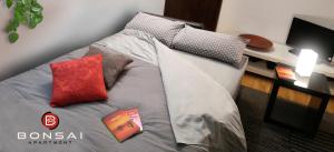 都灵Bonsai Apartment的一张带红色枕头的床和一本书