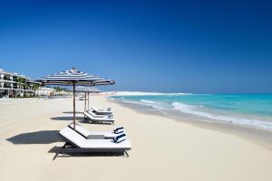 阿莱曼Al Alamein Hotel的海滩上的一组躺椅和遮阳伞