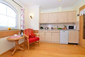 奥伯约赫Landhaus Hubert's Hüs的厨房配有红色椅子、桌子和窗户