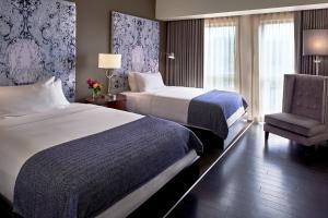 堪萨斯城The Fontaine的酒店客房,配有两张床和椅子