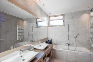奥伯古格尔Hotel Alpina deluxe的浴室配有2个盥洗盆、浴缸和淋浴。